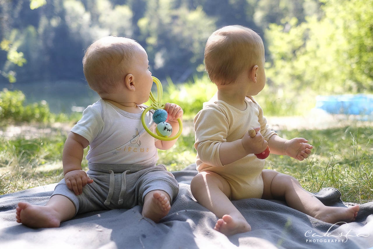 Deux bébés assis en tenue d'été au bord d'un lac naturel regarde tout les deux dans la même direction