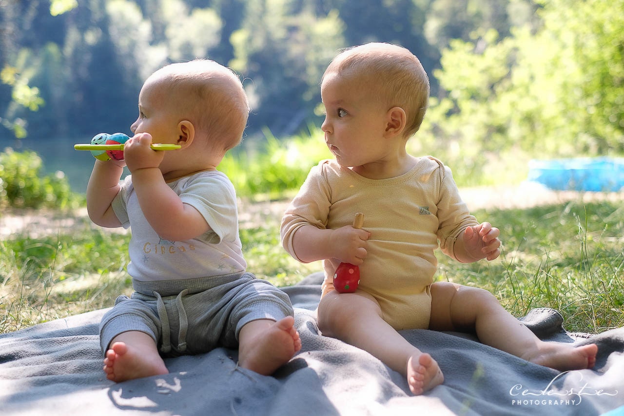 Deux bébés assis sur une couverture au bord d'un lac naturel en été regarde tout les deux du même côté
