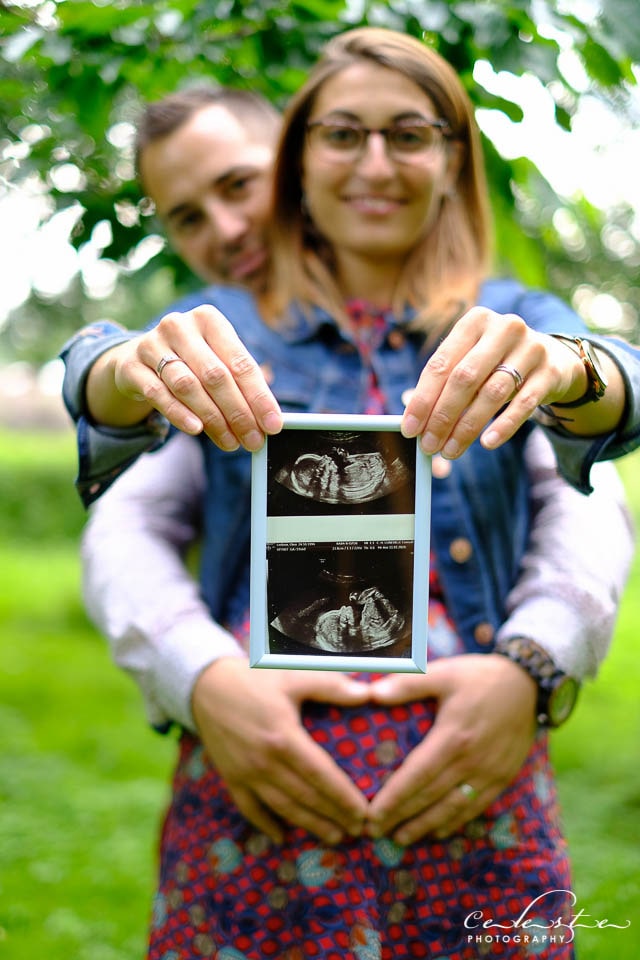 un couple montre une echographie de leur futur bébé en gros plan dans un jardin