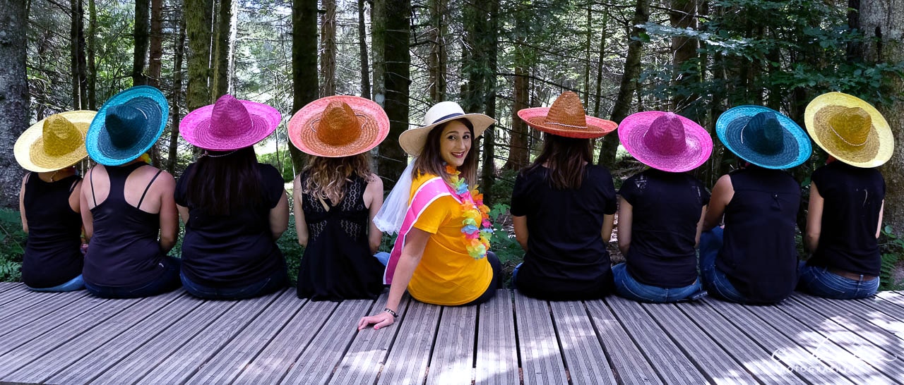 jeunes femmes à grand chapeaux colorés posant de dos pour un enterrement de vie de jeune fille seule la mariée au milieu regarde l'objectif