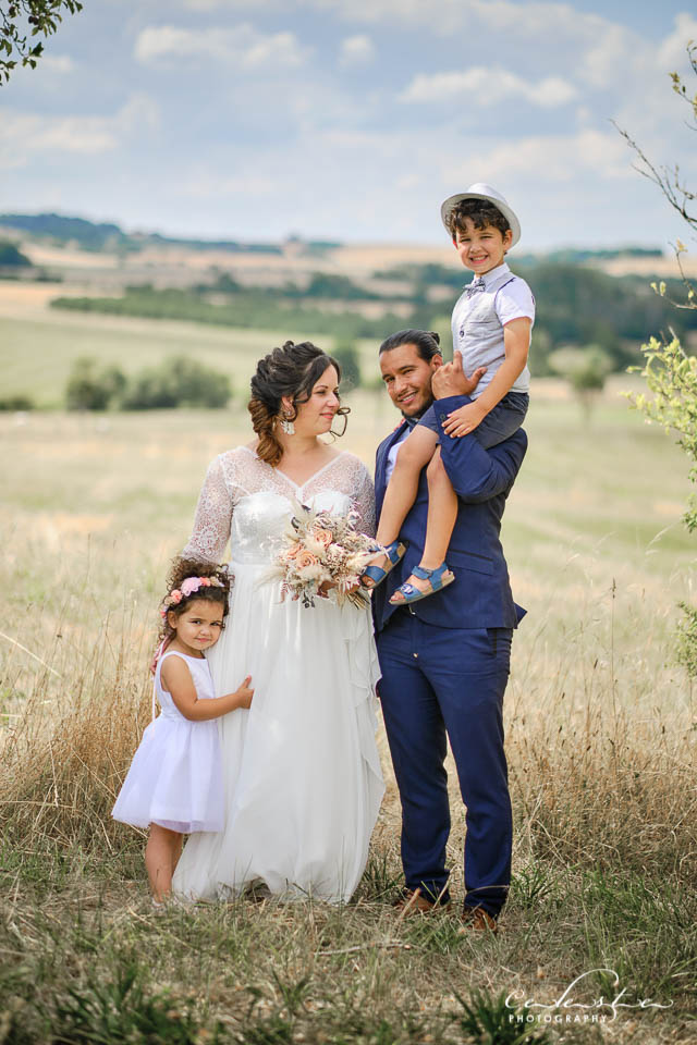 Des mariés avec leurs enfants posent pour la photos dans les champs