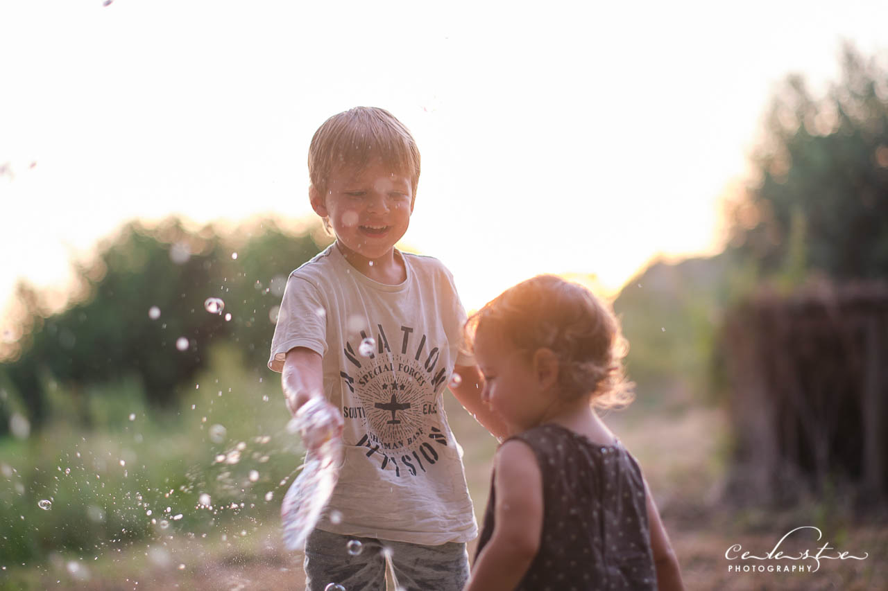 Des enfants s'amusent à faire des bulles dehors au soleil couchant